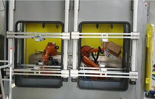 Blick auf zwei Roboter im Strahlraum der Injektor-Strahlanlage